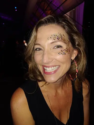Guest with gold and multicolored glitter glam scattered across her cheekbone