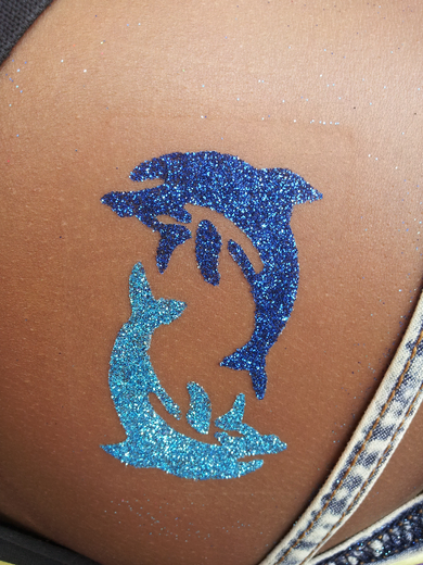 Two blue glitter dolphins on a guest's shoulder