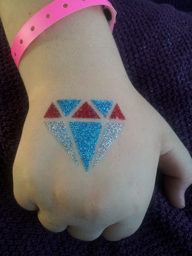 Red, silver and blue glitter diamond on the back of a child's hand