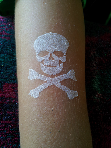 Silver glitter skull and crossbones on a forearm