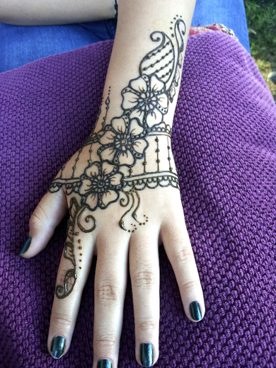 Henna flower and paisley bracelet design on the back of a hand