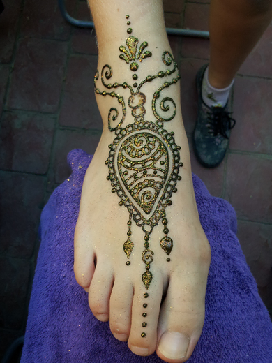 Henna foot design with a paisley medallion and gold glitter accents