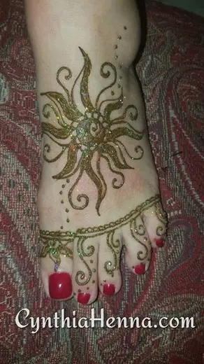 Henna sunburst on the top of a foot with a beaded toe-ring design