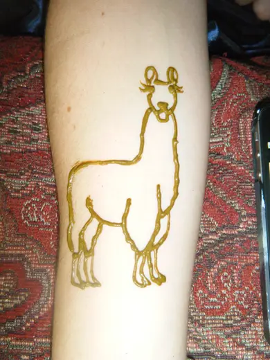 Fresh henna paste drawing of a llama on a forearm