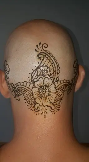 Henna crown of flowers and paisleys drawn on a shaved head
