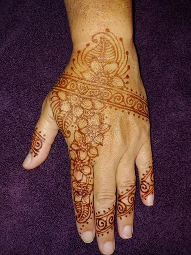 Henna flowers and a paisley band across the back of a hand