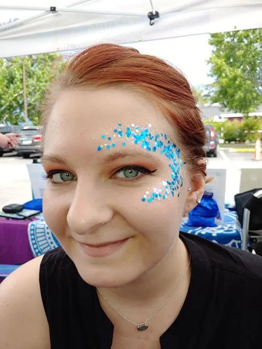 Festival glitter and glam: blue and white glitter with stars swept around a smiling guest's eye